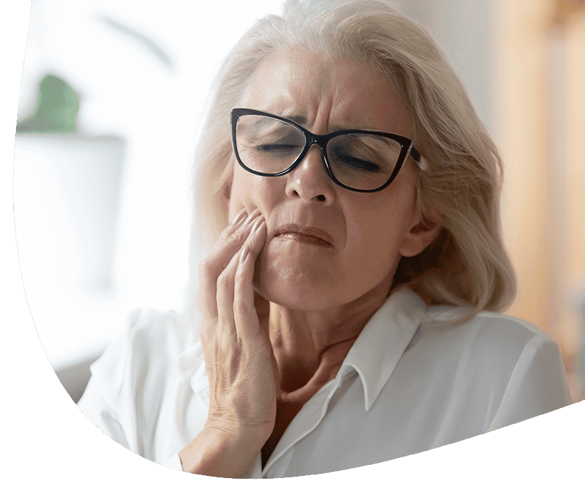 Staršia žena s bolesťou v tvári, ktorá si drží líce